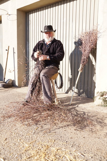 Alfred Judmaier sitzt völlig entspannt bei seiner Winterarbeit, dem Birkenbesenbinden.