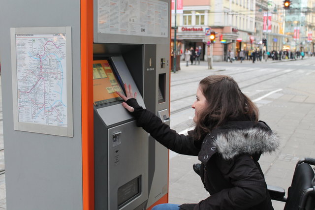 Magdalena Guschl hat keine Chance, die oberen Felder des Fahrscheinautomaten ohne fremde Hilfe zu erreichen.