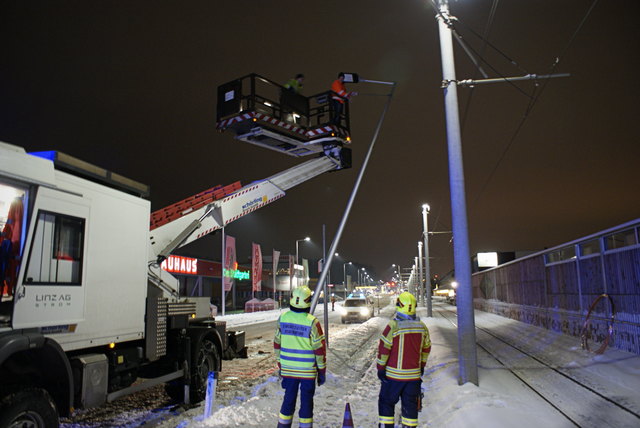 Einsatzkräfte der Freiwilligen Feuerwehr Pasching mit Experten der Linz AG bei der Demontage des Lichtmastens.