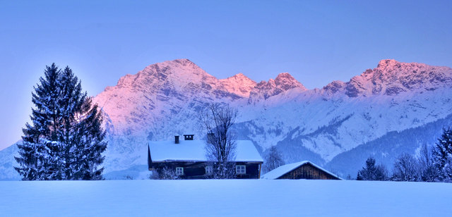 Kaps ist ein altes Haus in Saalfelden. Die Berge der Leoganger Steinberge im ersten Morgenlicht. Es ist sehr kalt.