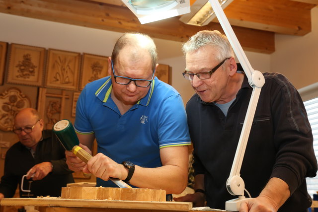 Kursleiter Franz Stadlhofer (r.) gibt den Schnitzkurs-Teilnehmern Tipps und hilft ihnen in entspannter Atmosphäre weiter.