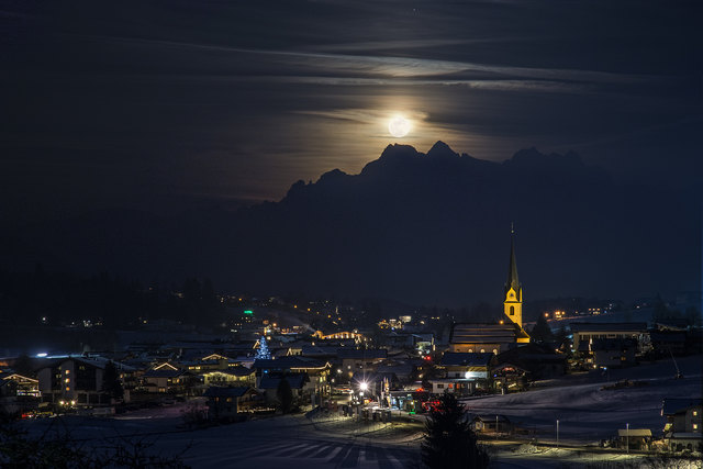 Der Februar-Vollmond (Schneemond) über den Loferer Steinbergen. Im Vordergrund das Bergdoktor-Dorf Ellmau.