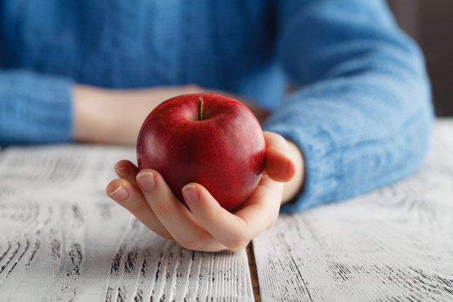 Girl holding red apple in hand