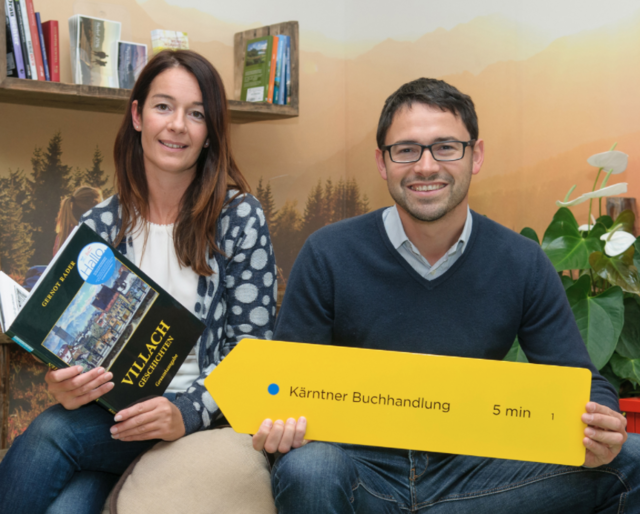 Martina Novak und Andreas Kuchler in der neuen Leseecke in der Tourismusinformation Villach