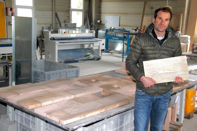 Hafnermeister Klaus Steinringer mit einer Fließe in Holzoptik.