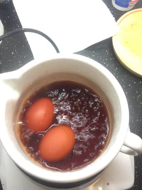 Eier färben mit Zwiebelschalen: den Farbsud abseihen und die Eier darin 20 Minuten kochen.