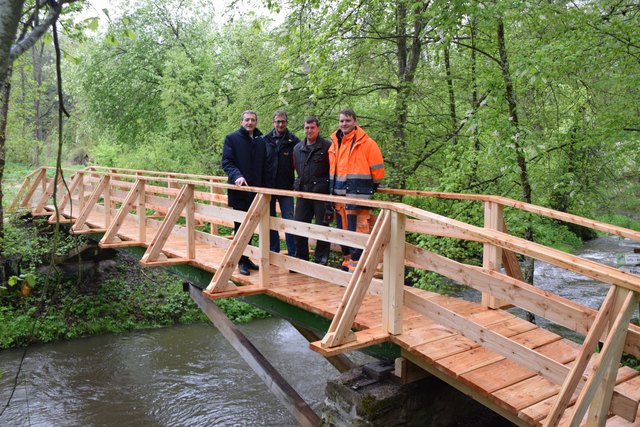 Bgm. LAbg. Jürgen Maier, Ing. Johannes Kapitan, die Bauhofmitarbeiter Jürgen Grecher und Christian Patzl bei der „Belastungsprobe“ der frischsanierten Holzbrücke im Taffatal.