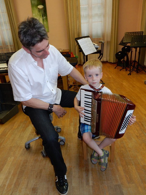 Musikschullehrer Günter Freiberger mit einem jungen Mann, der die Steirische Harmonika ausprobiert.