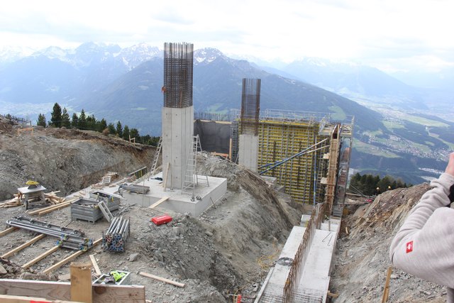 Baustelle 3 – Bergstation: Die metertiefen Verankerungen der Betonfundamente sind fertig, ebenso bereits Teile der Fassade. Aufgrund der Windverhältnisse ist für die Arbeiter höchste Vorsicht geboten.