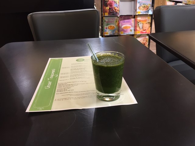 Menge: 0,125 l. Jeden Tag werden die Smoothies in der Früh vorgefertigt. Zutaten: Kale Pulver, Römersalat, Spinat, Petersilie, Ingwer, Zitrone, Birne, Datteln und Wasser. Er war extrem dickflüssig und man hätte die Zutaten nie erraten: Am ehesten schmeckte er nach frischgemähtem Gras.