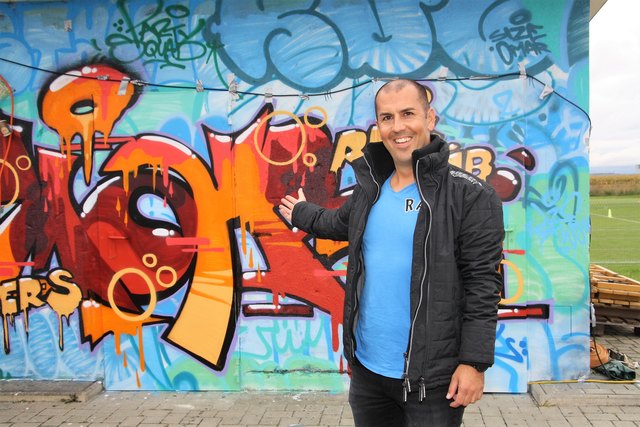 Patrick Trummer vor dem Jugendcontainer mit der Graffiti-Kunst von Sizetwo.