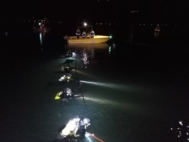Trainieren für den Ernstfall: Taucher von Wasserrettung und Feuerwehr gemeinsam in Kette mit Suchstangenverbindung, abgesichert durch ein Einsatzboot der Wasserrettung.