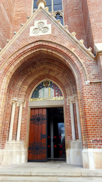 Der Turm der dreischiffigen Hallenkirche ist direkt über dem Hauptportal platziert, in dessen Tympanon ein den hl. Laurentius darstellendes Mosaik zu sehen ist