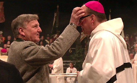 Vater Hermann Glettler macht seinem Sohn Hermann vor Beginn des Weihegottesdienstes ein Kreuz mit Weihwasser auf die Stirn. Mit dem Segen der Eltern und seiner Taufpatin beginnt der Innsbrucker Bischof seinen Dienst.