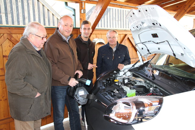 Karl sen., Karl und Florian Brandl gemeinsam mit Bürgermeister Josef Ober beim Laden eines neuen E-Fahrzeuges.