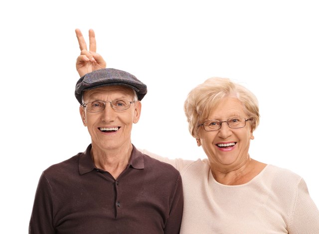 Elderly woman pranking her husband with bunny ears isolated on white background