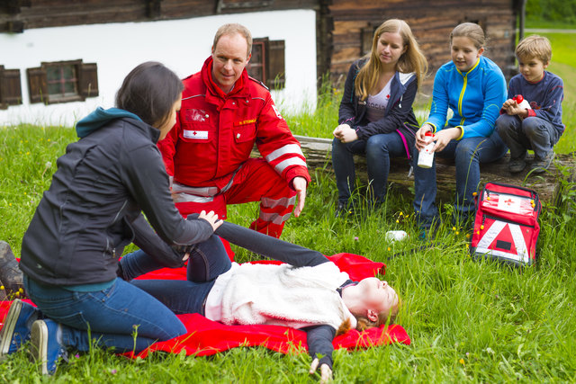 Kinder und Jugendliche beim Trainieren von Erste-Hilfe-Maßenahmen. Ein Mitarbeiter des Roten Kreuzes zeigt ihnen, wie es geht.