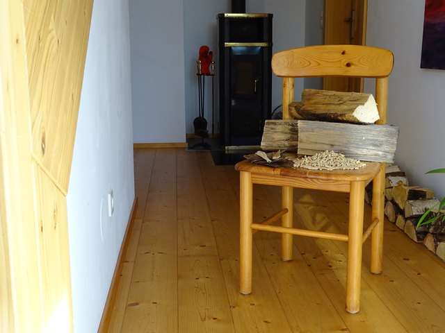 Brenn-Holz: Scheite, Schnitzel, Pellets und ein alter Sessel auf Holzfußboden in einer Holzmansarde.