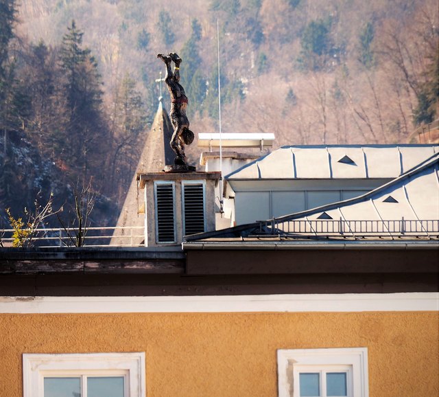 Ein Handstand am Hausdach ist vielleicht eine nette Alternative zum Fitnessstudio! Die Figur thront am Dach eines mehrstöckigen Hauses in Hallein.