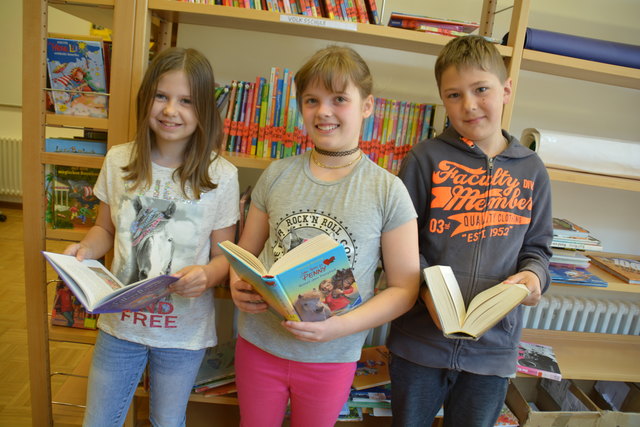 Die Schüler Selina, Madeleine und Simon von der Privaten Volksschule in Gleiß in der hauseigenen Bibliothek.