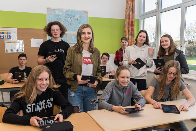 Schüler der vierten Klasse NMS Rohrbach (sitzend) und Schüler des Fachbereiches IT und Mediendesign der PTS Rohrbach (stehend) in einer Klasse mit Tablets.