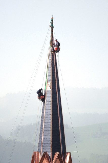 Die Arbeiter bringen in 70 m Höhe die letzten Schieferplatten an.