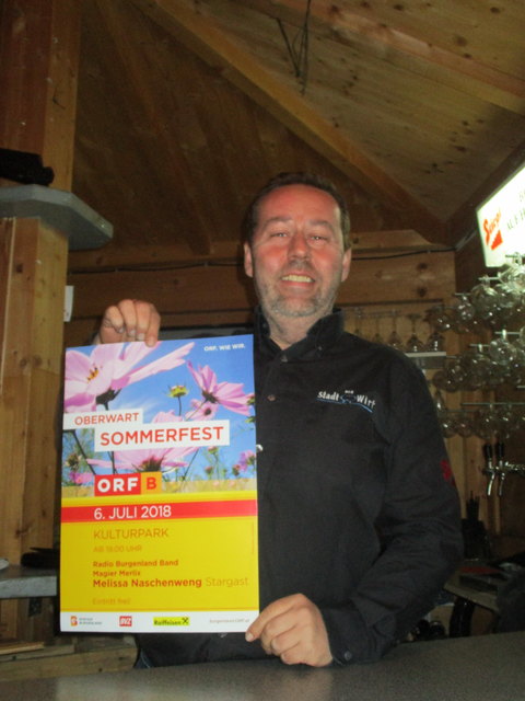 Raimund Schmidinger präsentiert das Plakat zum ORF Burgenland Sommerfest Anfang Juli. Schmankerl und gute Getränke gibt's dann vom Stadtwirt im Stadtpark.