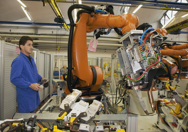 Techniker steuert Industrieroboter, der ihm die Arbeit erleichtert.