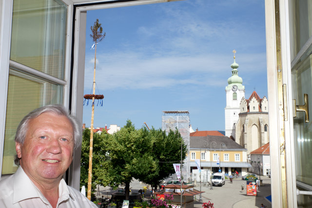 Blick vom Bürgermeisterbüro auf den Hauptplatz mit der eingerüsteten Dreifaltigkeitssäule vor der Kirche.