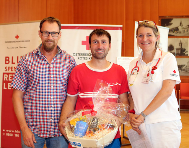 Daniel Kolber erhielt einen Geschenkkorb als Dankeschön; Dr. Claudia Feyerl vom Roten Kreuz und Peter Mitterecker, Gemeinde, gratulierten.