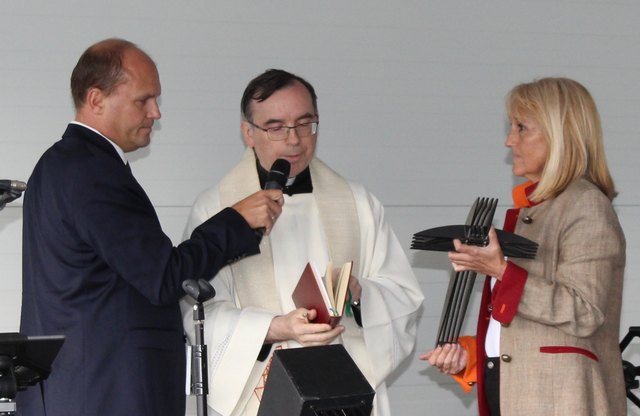 Moderator Burgholzer unterstützt Kaplan Purrer bei der Segnung eines Kreuzes für das Motel von Eva Wimmer (r.)
