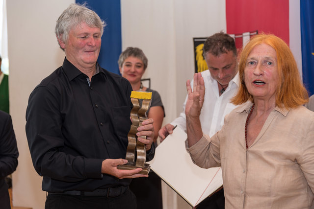 Edda Seidl-Reiter übergibt an Adolf Hofstetter die Bronzeskulptur bei der St. Anna-Preisverleihung.