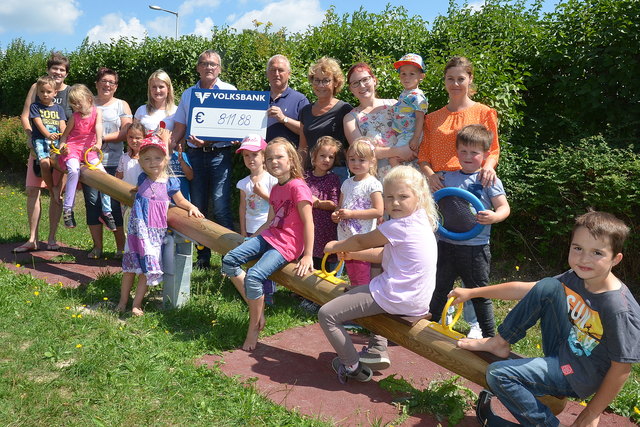 Die Kinder mit dem Kindergartenteam und den Spendern Joseph Klaffenböck und Hubert Razenberger (RHS Montagen) freuen sich über die neue Wippschaukel.