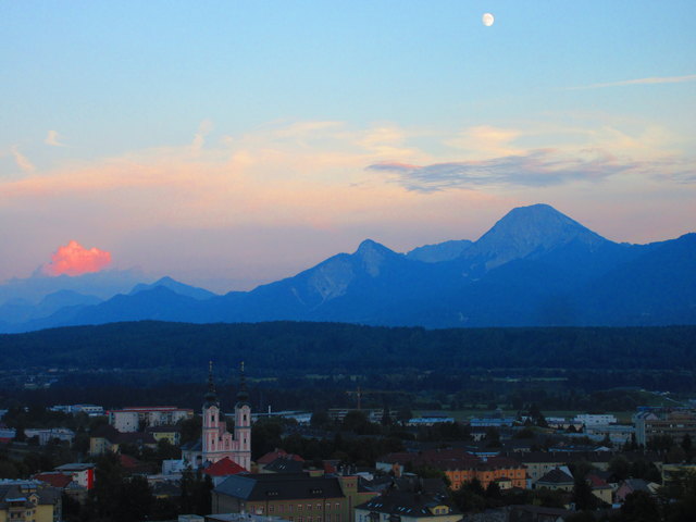 Abendstimmung, kurz vor Sonnenuntergang vom Turm der Stadtpfarrkirche aus gesehen. Der Mond über dem Mittagskogel und eine letzte, von der Sonne angestrahlte Wolke.