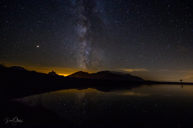 Spiegelung eines wunderbaren Sternenhimmels mit der Milchstrasse im Speichersee Arlensattel am Arlberg.