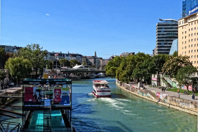 Die 'Blue Danube' pflügt stromaufwärts, um Besuchern unsere schöne Stadt zu zeigen, vorbei am Badeschiff. In der Bildmitte ist der Turm der Kirche 'Maria am Gestade' zu sehen