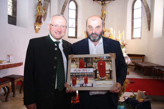 Bürgermeister Franz Xaver Hölzl überreichte Pfarrer Ireneuzs eine Bildcollage der Messfeier am Grab von Johannes Paul II bei der Pfarr-Romreise.