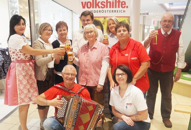 Bild: Volkshilfe Amstetten – Fritz Randa (v.l.n.r.): Cafe Schussi Geschäftsführerin Elena, Renate Höld, Rosi Steinkellner, Geschäftsführer City Center Amstetten Ing. Hannes Grubner, MSc, stellvertretende Volkshilfe Regionalvereinsvorsitzende Gemeinderätin Regina Öllinger, Traudi Ebner, Anita Wurzenberger (Sozialstation) und Claus Ludwig; vorne knieend: Musiker Hannes Steinlesberger und Elisabeth Bauer (Sozialstation)