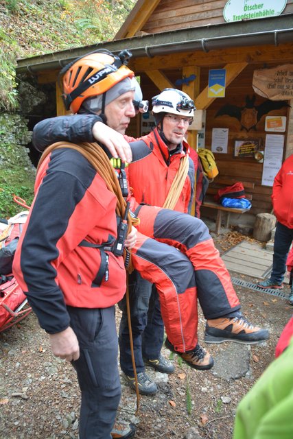 Zwei Personen tragen eine Verletzte mit dem Seil aus der Höhle.