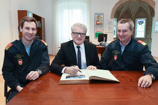 Bürgermeister Klaus Luger dokumentiert im Gedenkbuch die Eröffnung der generalsanierten Feuerwache Nord, in Anwesenheit von Branddirektor Christian Puchner (re.) und seinem Stellvertreter Stefan Krausbar (li.).  | Foto: Stadt Linz