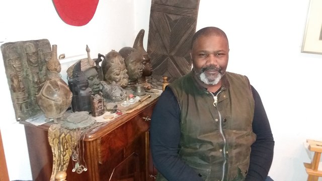 Nick Monu zu Hause. Hinter ihm, Kunstwerke aus dem ehemaligen westafrikanischen Königreich Benin. | Foto: Clément de Dravo