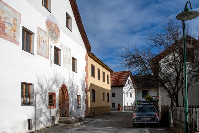 Bild 57: Durchsicht (über eine Quergasse) zum Burschlweg. Die Objekte im Hintergrund sind dem Burschlweg zugeordnet mit den Hausnummern 5, 4, 2a (links) und Nr. 3 (rechts).

Hier sieht man die Südfassade mit dem gekehlten Spitzbogenportal und den daneben liegenden Fenster mit spätgotischen Gewände und Eisengitter (siehe auch Bild 58). Am rechten Rand noch ein Stück des Baumgartens welcher nicht als Parkplatz genutzt wird. Siehe dazu die Bilder 51 + 52.  | Foto: © by Ing. Günter Kramarcsik