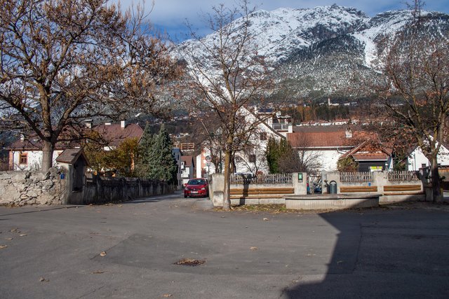 Bild 51: Der Perfuchser Dorfplatz mit dem 1987 neu errichteten Dorfbrunnen und mit seiner Fortsetzung der Herzog- Friedrich- Straße auf der linken Seite mit  Durchsicht zu Haus Nr. 36 (ehemaliges Gasthaus).

Hinter dem Dorfbrunnen ist ein weiterer eingezäunter Platz, welcher heute als Parkplatz dient. Früher diente er als Thingstätte (siehe Bild 52). Thingversammlungen waren eine frühe germansiche Form einer demokratischen Mitbestimmung. | Foto: © by Ing. Günter Kramarcsik