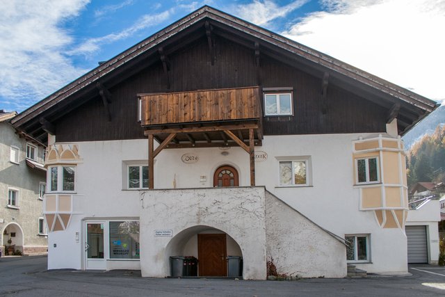 Bild 49: Haus Nr. 33 war in der Vergangenheit eine lange Zeit ein Musterbeispiel für künstlerische Fassadengestaltung und gefällige architektonische Proportionen.  Unsensible Renovierungen und Umbauten  (z.B. aufgeständerter Balkon über Eingangsportal) und überdimensionierte Fenster im EG wirken sich leider unvorteilhaft aus. Trotz der unvorteilhaften Veränderungen bildet dieses Eckhaus noch einen schönen Abschluss des Dorfplatzes nach Süden.  | Foto: © by Ing. Günter Kramarcsik
