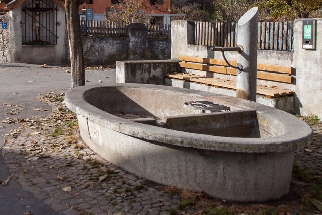 Bild 54: Der alte Granitdorfbrunnen wurde 1987 durch diesen Betonbrunnen ersetzt. Im Winter ist der Brunnen "trocken gelegt". Rechts dahinter befindet sich die in den Bildern 51 + 52 beschriebene Thingstätte. | Foto: © by Ing. Günter Kramarcsik