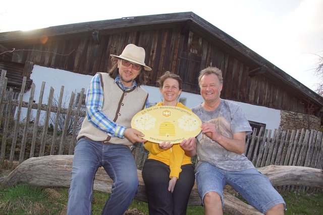 Anton Erlacher (l.) vom Verein Bienenschutzgarten überreicht im Rahmen der österreichweiten Aktion die erste Plakate an Maria Schietz und Helmut Eder für einen bienenfreundlichen Garten am Unterkagererhof.