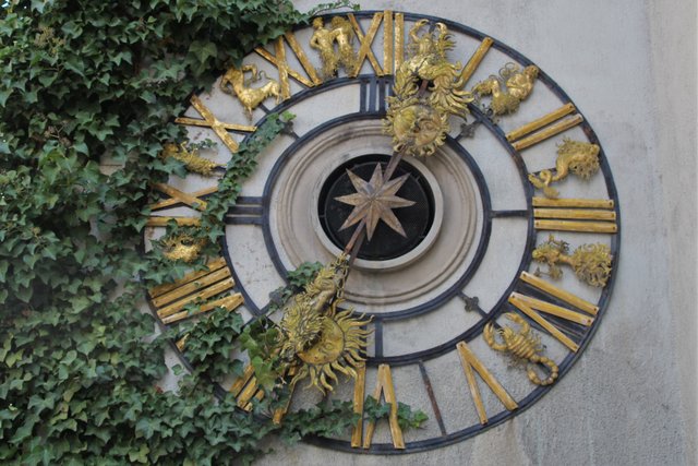 Spezielle "Sternzeichen-Uhr" an einer Hausmauer geschmückt mit  Efeu