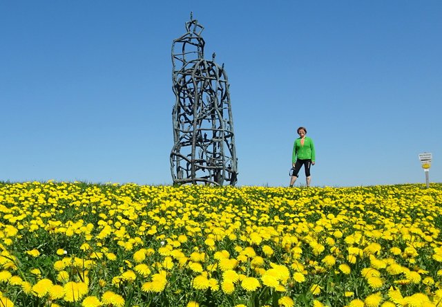 Bei der 7 m hohen Bronzeskulptur, die auf Grund seiner Form und des Fernblicks „Weltwegbetrachter“ benannt wurde. Sie steht seit 2007 auf einer AnhöheRichtung Hochkogel. ...mitten im gelben Löwenzahnteppich!!!