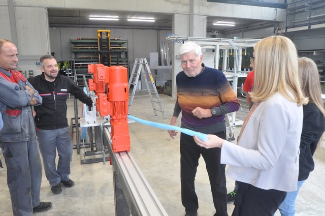 M. Schramböck mit Senior-Chef Edi Steinbacher und Arbeitern in einer Werkshalle. | Foto: Kogler