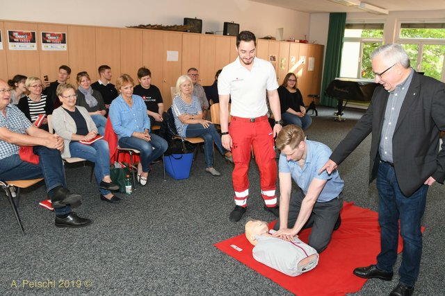 Ein Kursteilnehmer übt an einer Puppe die Herzmassage. Mit im Bild Sebastian Meier und Bürgermeister Ferdinand Köck.